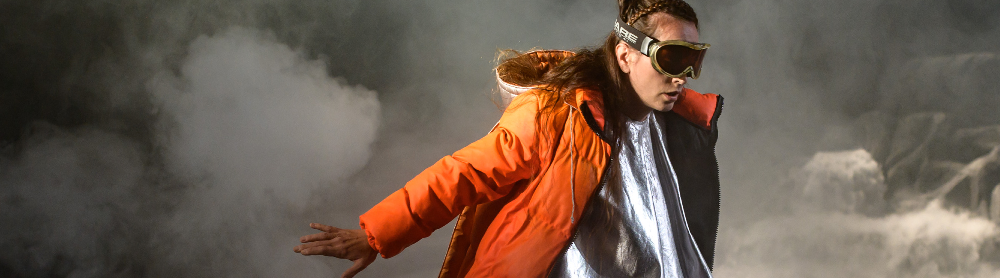 Das Bild zeigt eine Frau mit Skibrille und einer orangefarbenen Jacke.