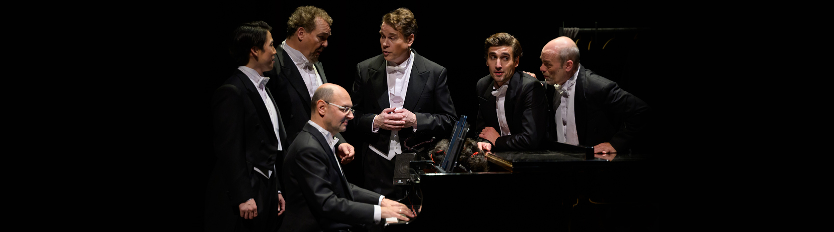 Szenenfotos der Inszenierung »Heute Nacht oder nie«: Fünf Männer in schwarzen Fräcken stehen singen rund um ein Klavier, an dem ein Pianist sitzt und sie begleitet. Stückbild des Stückes Heute Nacht oder nie